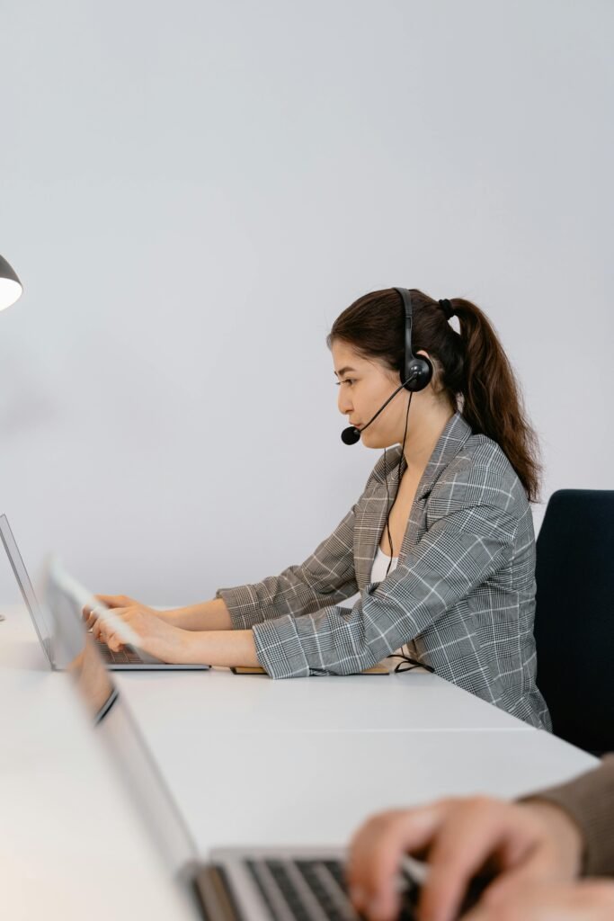 Focused call center agent wearing headphones providing customer support in a modern office.
