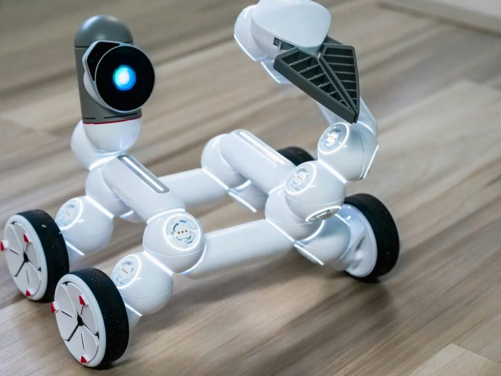 Close-up of a flexible modular robot with wheels on a wooden floor, showcasing modern robotics technology.